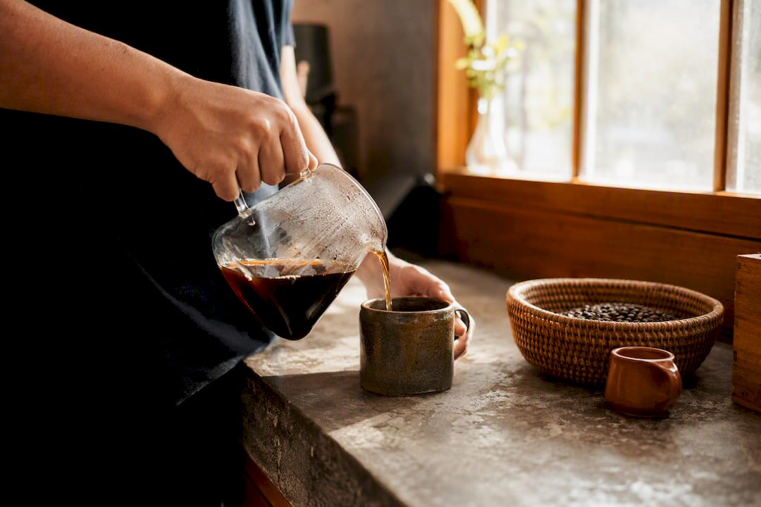 Hands pouring low acid coffee into cup